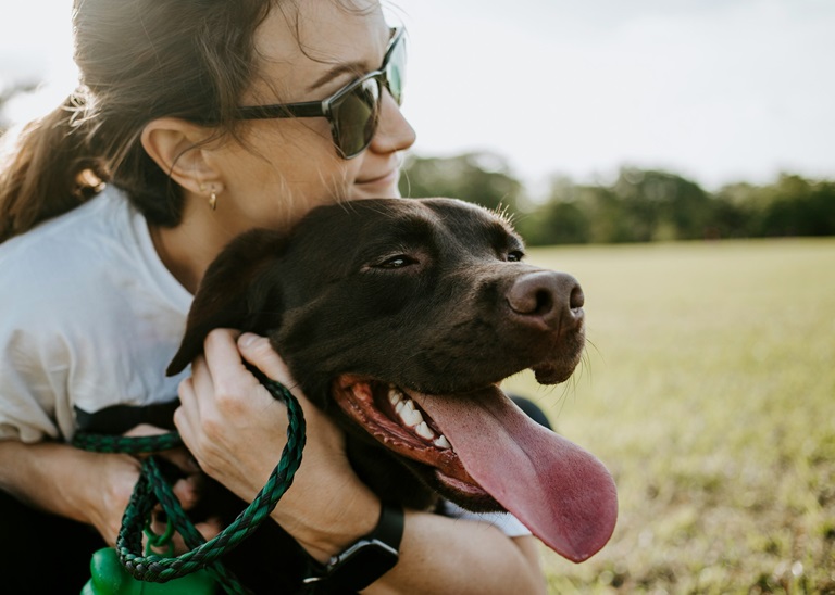 a woman in sunglasses hugging a dog at The Waterchase Gardens
